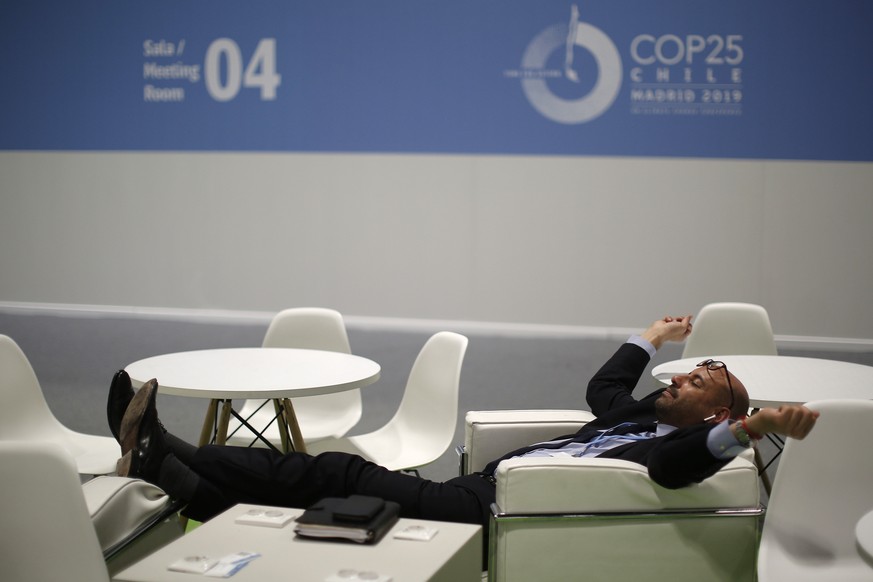 A visitor rests at the COP25 climate talks congress in Madrid, Spain, Saturday, Dec. 14, 2019. The United Nations Secretary-General has warned that failure to tackle global warming could result in eco ...