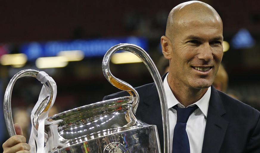 FILE - In this Saturday, June 3, 2017 file photo Real Madrid&#039;s head coach Zinedine Zidane celebrates with the trophy at the end of the Champions League soccer final between Juventus and Real Madr ...