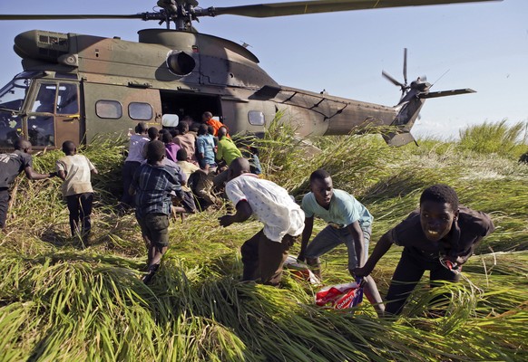 In this Tuesday, March 26, 2019, photo, residents make of with bags of rice in a scramble for food delivered by the South African Airforce helicopter at Nyamatande Village, Mozambique, following the d ...