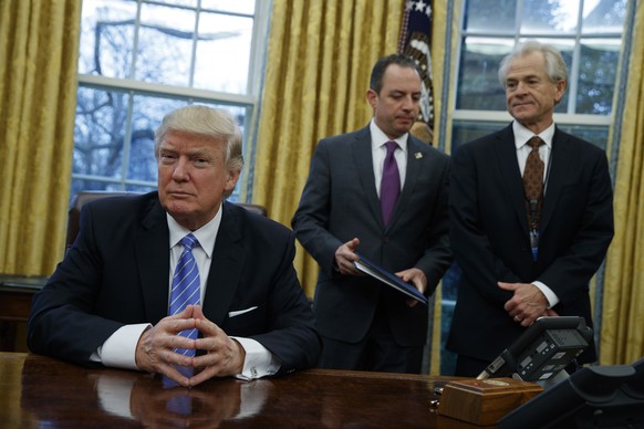 National Trade Council adviser Peter Navarro, right, and White House Chief of Staff Reince Priebus, center, await President Donald Trump&#039;s signing three executive orders, Monday, Jan. 23, 2017, i ...