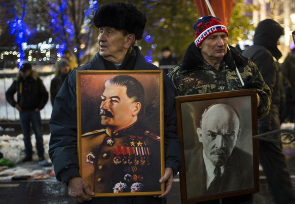 Two men hold portraits of Soviet dictator Josef Stalin, left, and Soviet Founder Vladimir Lenin during a demonstration marking the 99th anniversary of the 1917 Bolshevik revolution in Moscow, Russia,  ...