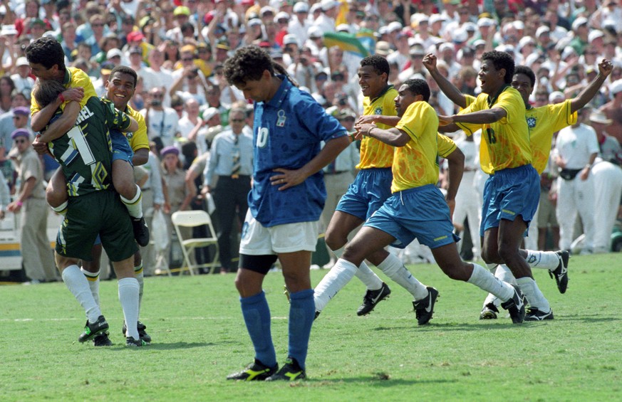Brazilian striker Bebeto leaps into the arms of goalkeeper Claudio Taffarel (L) as Italy&#039;s Roberto Baggio (C) stares at the ground after missing the penalty kick which cost his team the World Cup ...