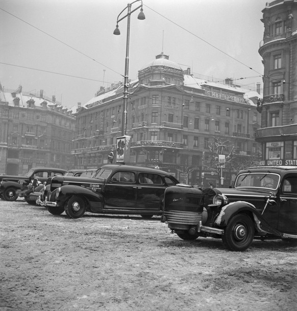 Taxi-Chauffeure im Dienst in winterlichen Zuerich haben ihre Fahrzeuge auf dem Platz vor dem Hauptbahnhof Zuerich stehen, aufgenommen im letzten Kriegsjahr am 25. Januar 1945. (KEYSTONE/PHOTOPRESS-ARC ...