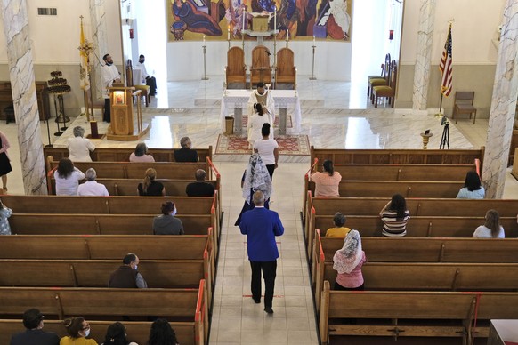 Worshippers stand on premarked tape lines to receive the Eucharist from the Rev. Enrique Corona, top center, during a Mass at St. Agnes Church in Paterson, N.J., Sunday, June 14, 2020. New Jersey ease ...