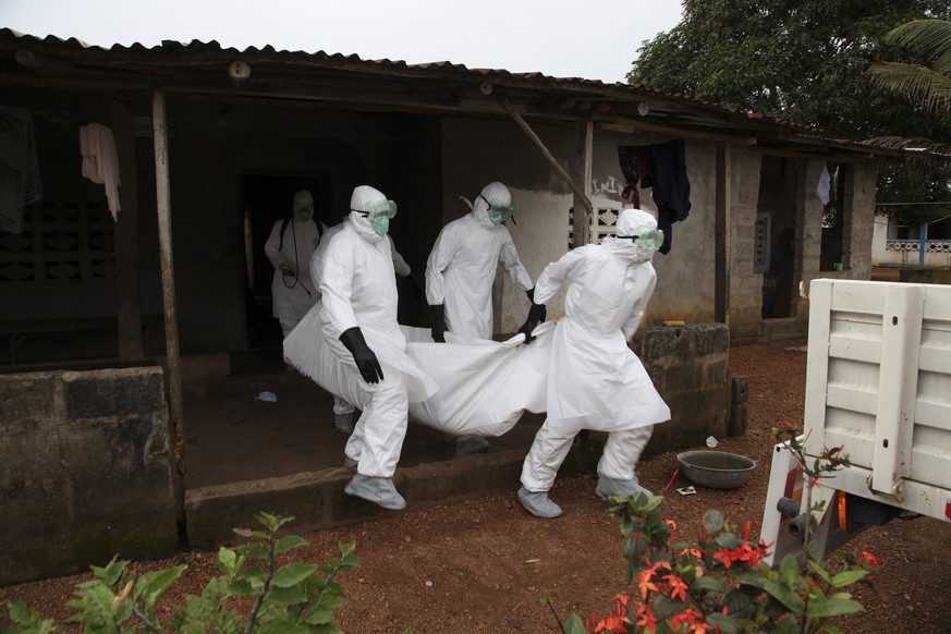 Sanitäter in Liberia tragen ein Ebola-Opfer aus einem Haus.