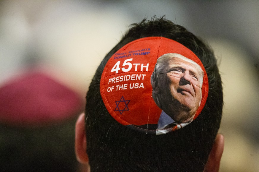 A man wearing a yarmulke with President Donald Trump face listens as Bradley Laye, president and CEO at the Jewish Federation of Greater Dallas, gives remarks during a community service of hope and he ...