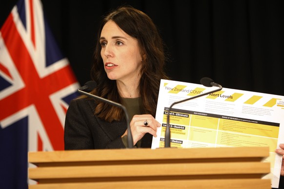 New Zealand Prime Minister Jacinda Ardern holds up a card showing a new alert system for COVID-19, Saturday, March 21, 2020, in Wellington, New Zealand. For the first time in New Zealand, health autho ...