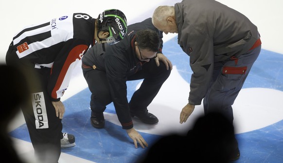 Geneve-Servette&#039;s Head coach Chris McSorley, center, between Head referee Stefan Eichmann, left, and a technician, right, looks on a hole into the ice, during the Swiss Ice Hockey Cup round of 16 ...