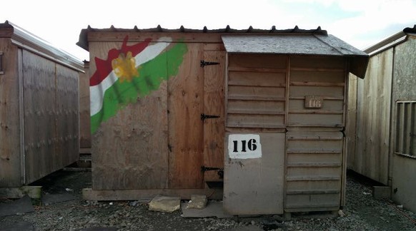 In diese Hütten kehrten die Flüchtlinge nach ihrer gescheiterten Flucht zurück. Am Eingang ist eine Kurdistan-Flagge ausgemalt.