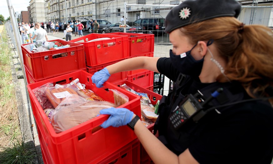 epa08502029 A policewoman helps to deliver food for quarantined employees of the meat processing company Toennies in the district Suerenheide in Verl, 22 June 2020. According to media reports, over 13 ...