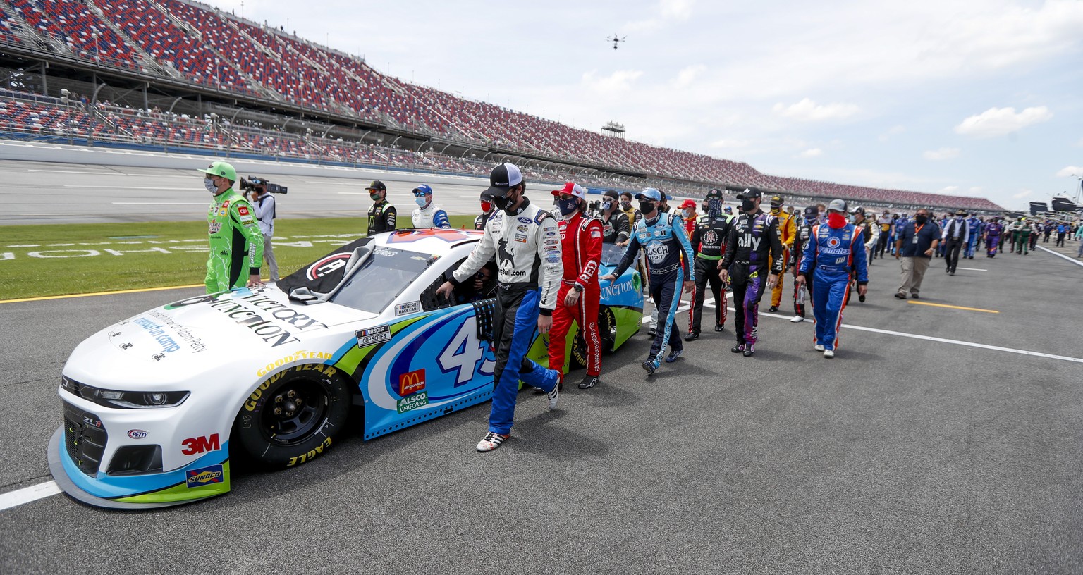 Nascar drivers Kyle Busch, left, and Corey LaJoie, right, join other drivers and crews as they push the car of Bubba Wallace to the front of the field prior to the start of the NASCAR Cup Series auto  ...