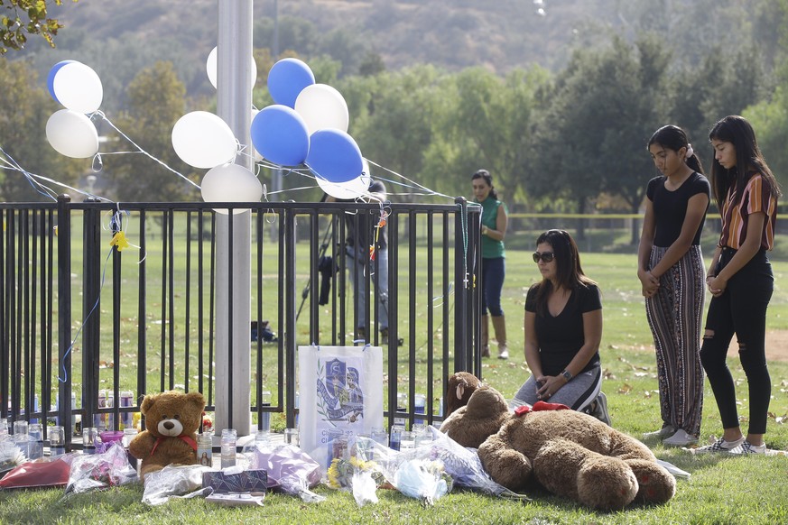 Parent Mirna Herrera kneels with her daughters Liliana, 15, and Alexandra, 16 at the Central Park memorial for the Saugus High School victims in Santa Clarita, Calif., Friday, Nov. 15, 2019. Investiga ...
