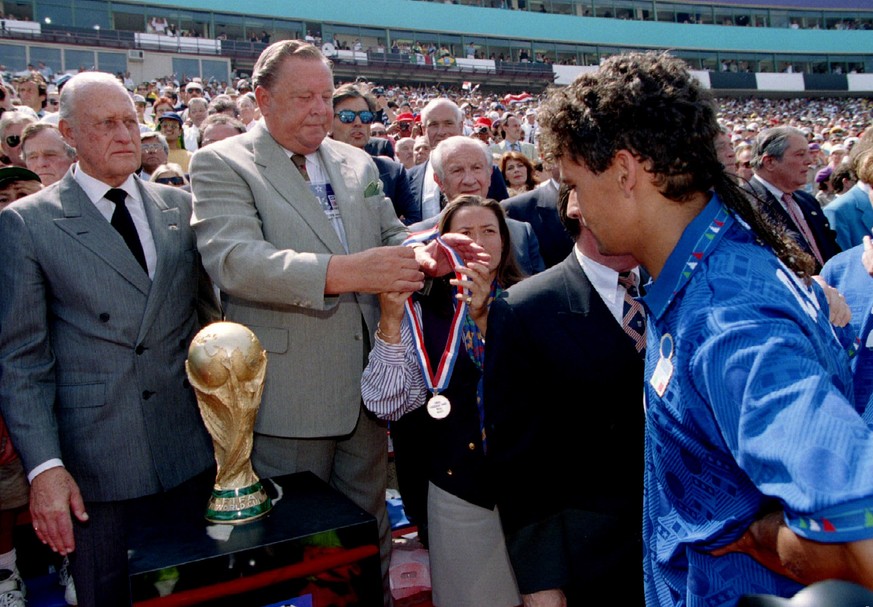 Italian star forward Roberto Baggio stares at the World Cup trophy July 17 during the second place medals presentation. FIFA President Joao Havelange (L) and Guillermo Canedo (C), Chairman of the Orga ...