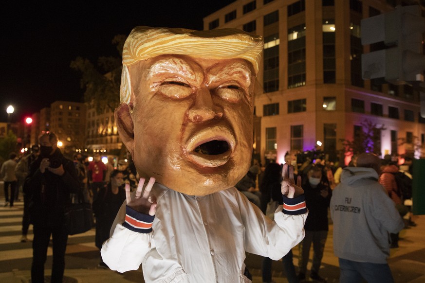 epa08797277 A woman wears a mask depicting US President Donald J. Trump at Black Lives Matter Plaza in Washington, DC, USA, 03 November 2020. Americans vote on Election Day to choose between re-electi ...