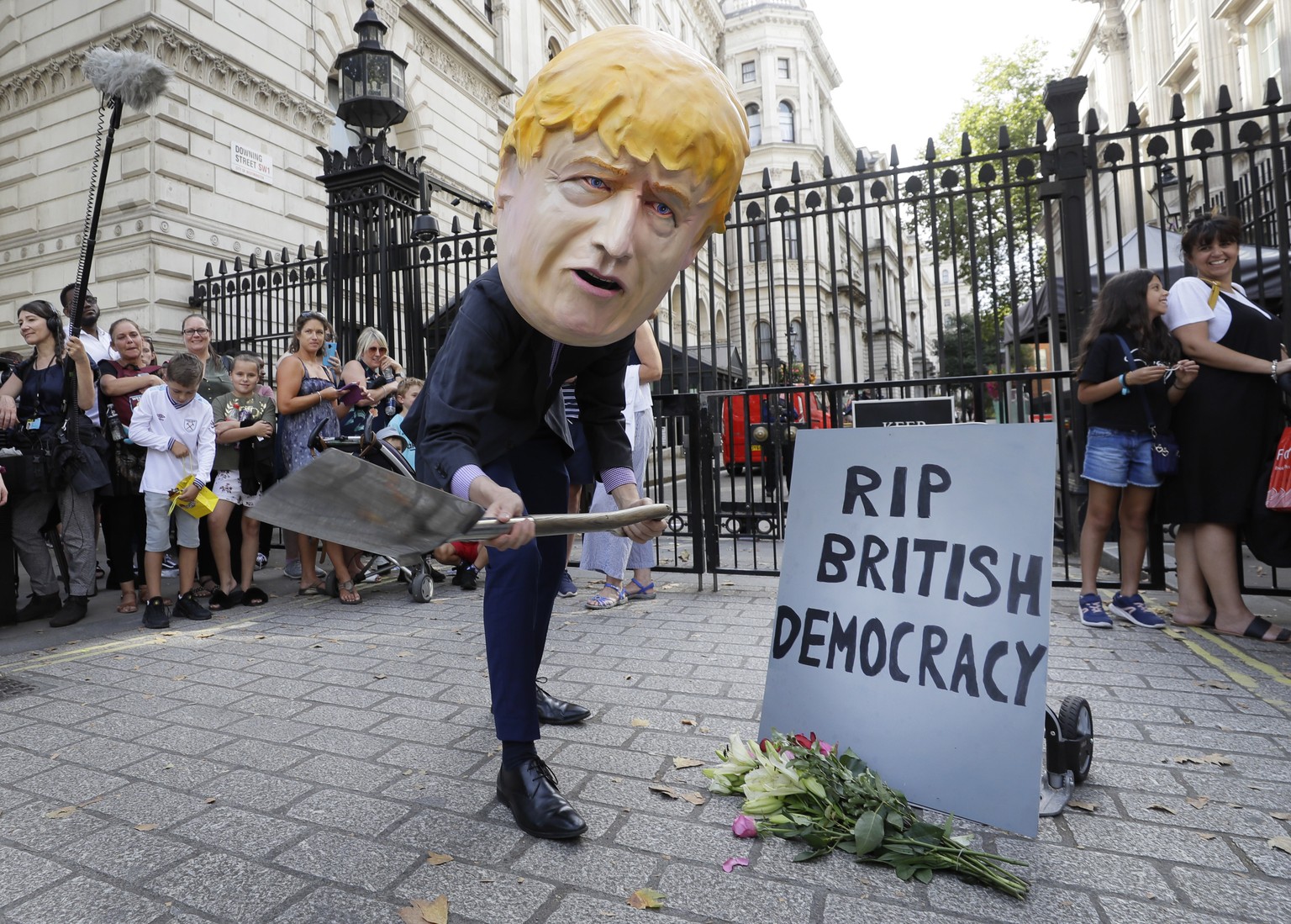 A man in a giant Boris Johnson &#039;head&#039; digs a grave at the foot of a pretend tombstone outside Downing Street in London, Wednesday, Aug. 28, 2019. Britain&#039;s Queen Elizabeth II has approv ...