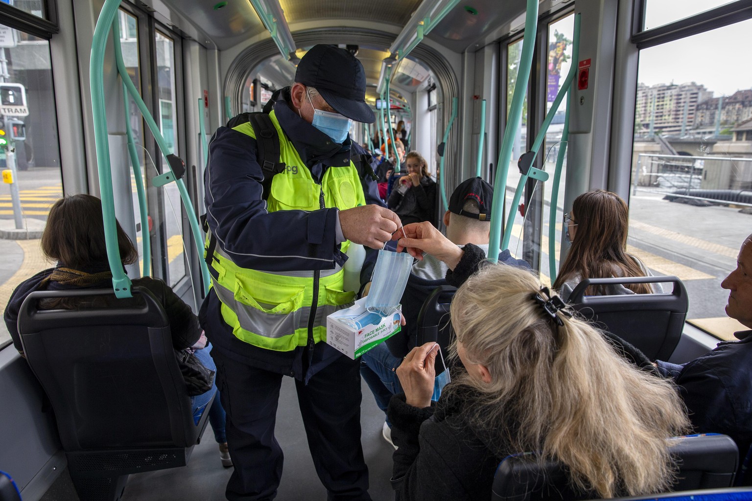 A member staff of the Transports publics genevois, TPG, (English: Geneva Public Transport), distributes protective face masks as a preventive mesure against the spread the coronavirus COVID-19 to pass ...
