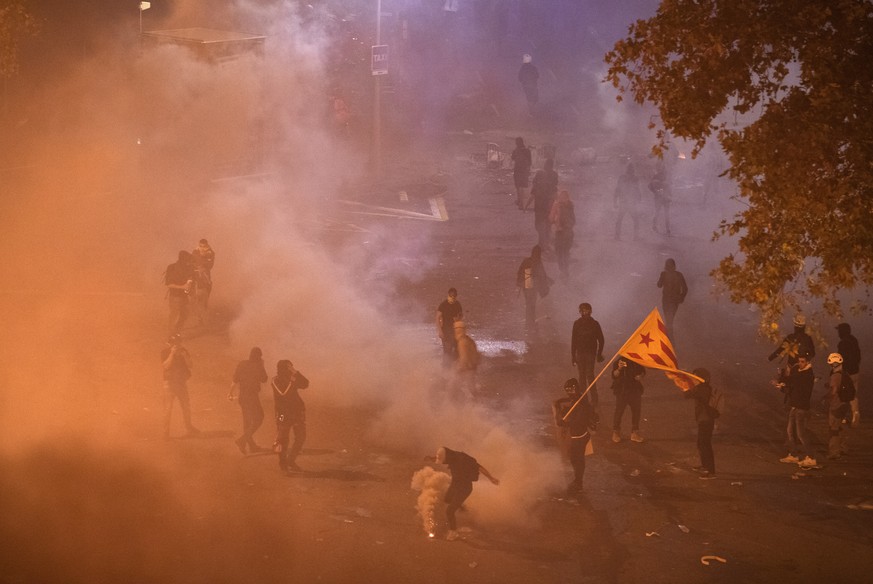 Protesters are dispersed by teargas thrown by national police officers, during clashes in Barcelona, Spain, Friday, Oct. 18, 2019.The Catalan regional capital is bracing for a fifth day of protests ov ...