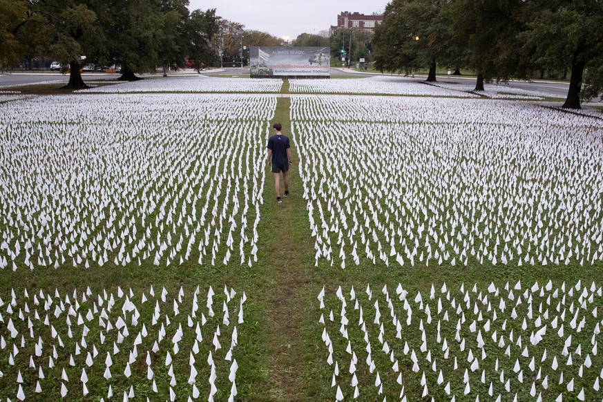 epaselect epa08777747 A pedestrian looks at some of the hundreds of thousands of white flags placed in a memorial for people who died with COVID-19, at the DC Armory Parade Ground outside RFK Stadium  ...
