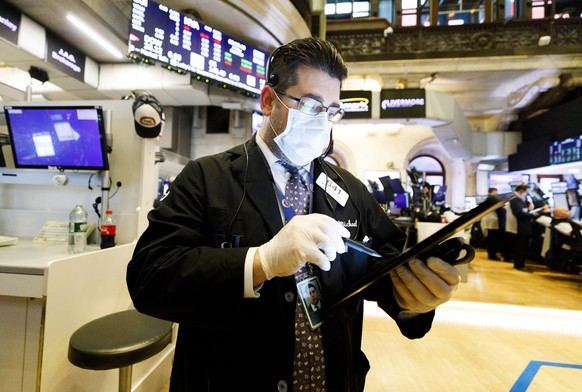 epa08309458 Trader Michael Capolino wears a protective mask while working on the floor of the New York Stock Exchange in New York, USA, 20 March 2020. The New York Stock Exchange will stop floor opera ...
