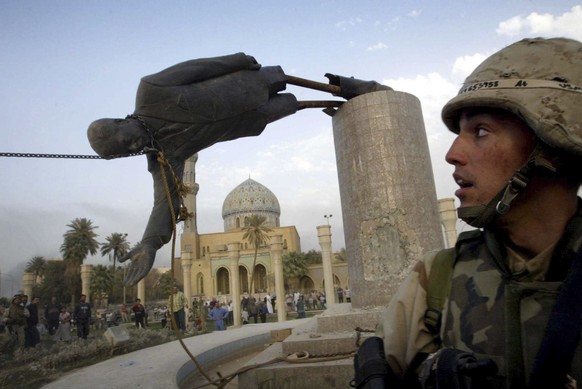 U.S. Marine Corp Assaultman Kirk Dalrymple watches as a statue of Iraq&#039;s President Saddam Hussein falls in central Baghdad&#039;s Firdaus Square in this April 9, 2003 file photo. To match Special ...