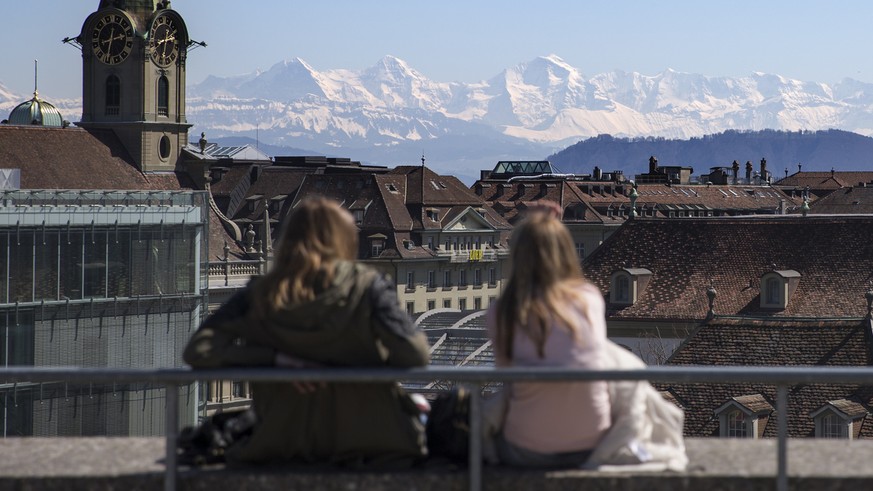 Zwei junge Frauen geniessen den Ausblick von der Grossen Schanze auf die Stadt und umliegenden Berge, am Mittwoch, 8. April 2015, in Bern. (KEYSTONE/Peter Klaunzer)