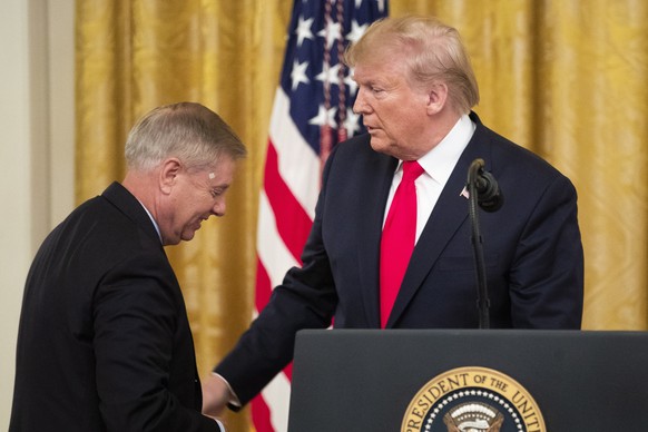 epa07977618 US President Donald J. Trump (R) turns over the podium to Republican Senator from South Carolina Lindsey Graham (L) during an event on federal judicial confirmations, in the East Room of t ...