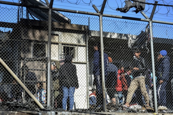 Migrants stand outside container houses in Moria refugee camp on the northeastern Aegean island of Lesbos, Greece, Monday, March 16, 2020. The Fire Service said a migrant, who was not further identifi ...