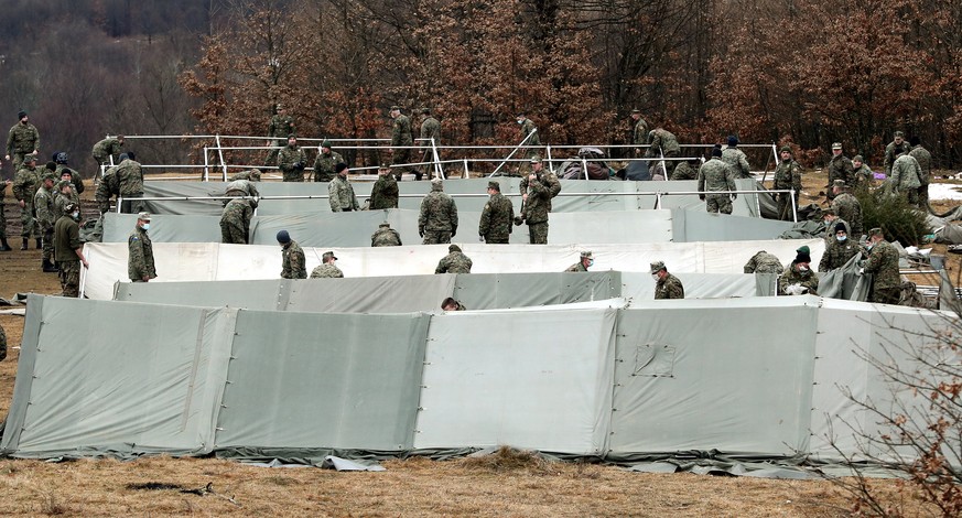 epaselect epa08914499 Bosnian soldiers set up new tents for migrants at the Lipa camp in Bihac, Bosnia and Herzegovina, 01 January 2021. Some thousand refugees at the camp were scheduled to be relocat ...