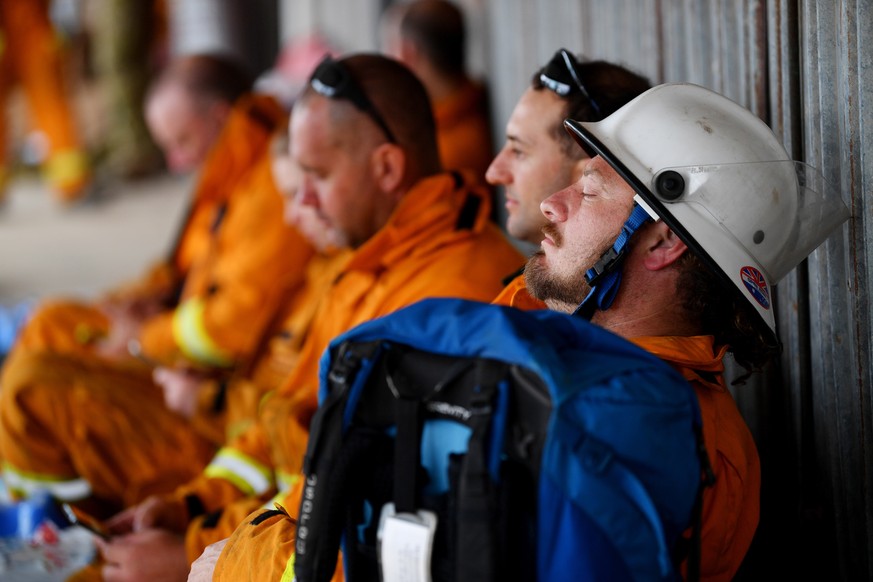 epa08115463 Firefighters rest at Kingscote oval after fighting fires through the night, on Kangaroo Island, southwest of Adelaide, Australia, 10 January 2020. Country Fire Service volunteers along wit ...