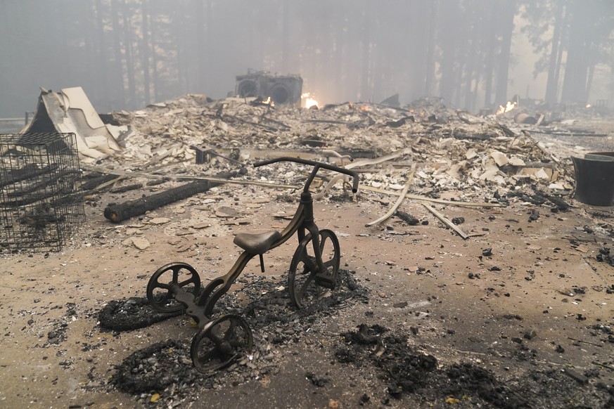 A charred tricycle is left behind in a fire-ravaged home after the CZU August Lightning Complex Fire in Thursday, Aug. 20, 2020, in Bonny Doon, Calif. (AP Photo/Marcio Jose Sanchez)
