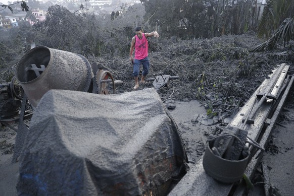 A man walks along ash fall covered plants and equipment as Taal Volcano continues to spew ash on Monday Jan. 13, 2020, in Tagaytay, Cavite province, south of Manila, Philippines. The small volcano nea ...