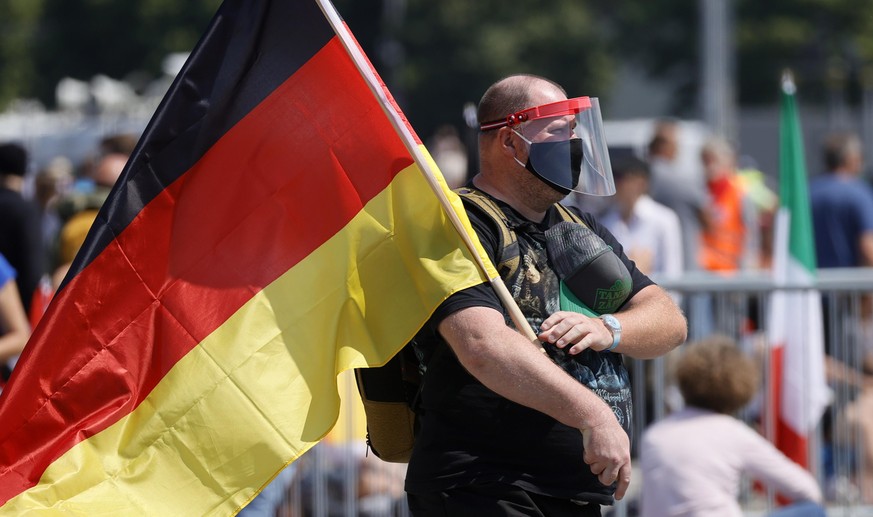 epa08426051 A man hold a German flag during a demonstration of the initiative &#039;Lateral thinking&#039; in Stuttgart, Germany, 16 May 2020. The demonstration is directed against the Coronavirus res ...