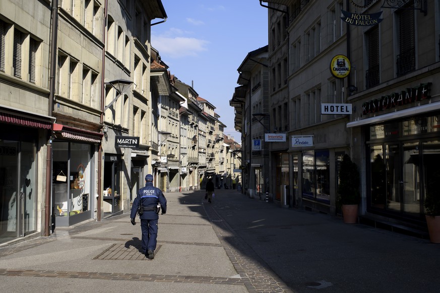 Un membre de la Police locale patrouille dans la Rue de Lausanne lors de la pandemie de coronavirus (covid-19), ce mercredi 25 mars 2020, a Fribourg. (KEYSTONE/Anthony Anex)