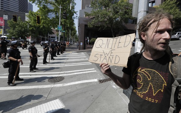 In this Aug. 18, 2018 file photo man holds a sign that reads &quot;Q-Nited We Stand&quot; during a rally held by members of Patriot Prayer and other groups supporting gun rights near City Hall in Seat ...