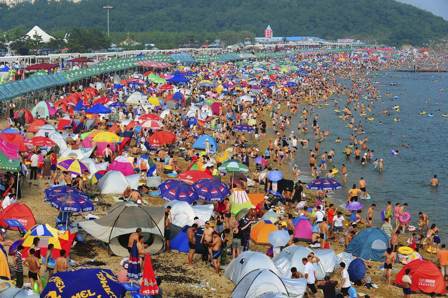 In this photo released by the Xinhua news agency, beach-goers enjoy their summer time at the Fujiazhuang lido, the largest lido in the urban area of Dalian in northeast China&#039;s Liaoning province, ...