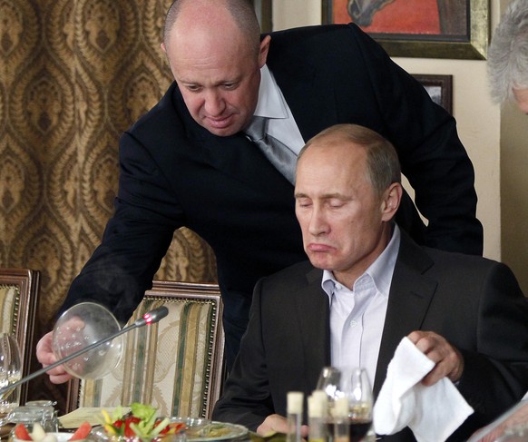 FILE - In this Friday, Nov. 11, 2011, file photo, Yevgeny Prigozhin, left, serves food to Russian Prime Minister Vladimir Putin during dinner at Prigozhin&#039;s restaurant outside Moscow, Russia. USA ...