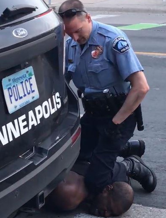 Ein Polizist drückt den Verhafteten minutenlang mit dem Knie auf den Boden.