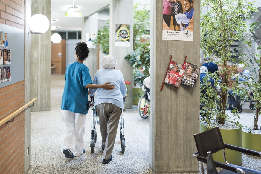 ARCHIV -- ZUM TAGESGESCHAEFT DER FRUEHJAHRSSESSION AM MONTAG, 18. MAERZ 2019, STELLEN WIR IHNEN FOLGENDES THEMENBILD ZUR VERFUEGUNG - A nurse walks next to a resident of the retirement home Herzogenmu ...