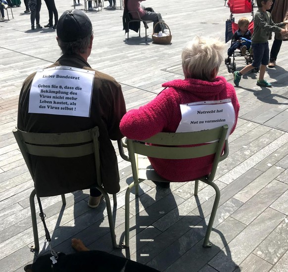 In Zürich sitzt ein Ehepaar auf Stühlen und beobachtet das Treiben. Auf ihren Rücken haben sie ein Papier mit einer Botschaft: «Lieber Bundesrat, geben Sie 8, dass die Bekämpfung des Virus nicht mehr  ...