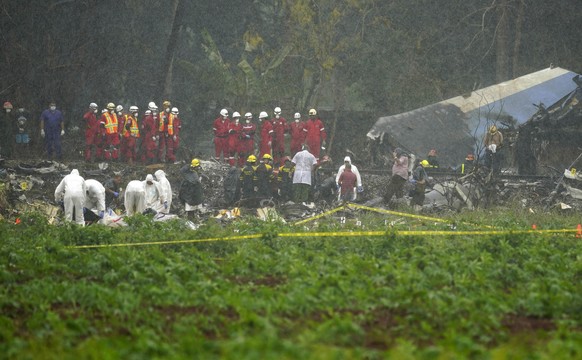 Rains begins to fall as rescue teams search through the wreckage site of Boeing 737 that plummeted into a yuca field with more than 100 passengers on board, in Havana, Cuba, Friday, May 18, 2018. The  ...