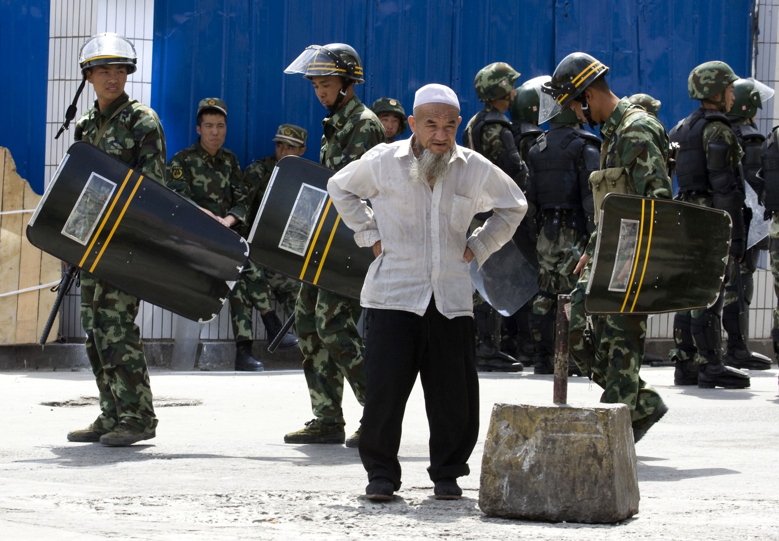 FILE - In this July 8, 2009, file photo, paramilitary police walk past an elderly ethnic minority man a day after Han Chinese mobs attacked Uighur in retaliation for earlier attacks in neighbourhoods  ...