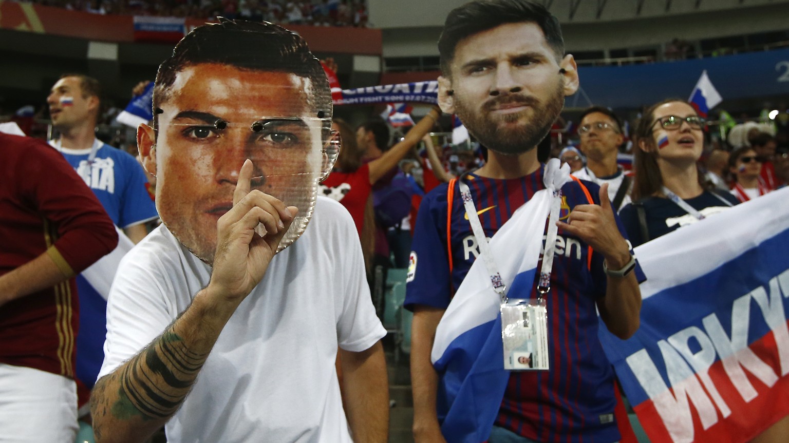 Fans wear masks with the face of the Portuguese national soccer star Cristiano Ronaldo and Argentina national soccer star Lionel Messi prior to the start of the quarterfinal match between Russia and C ...