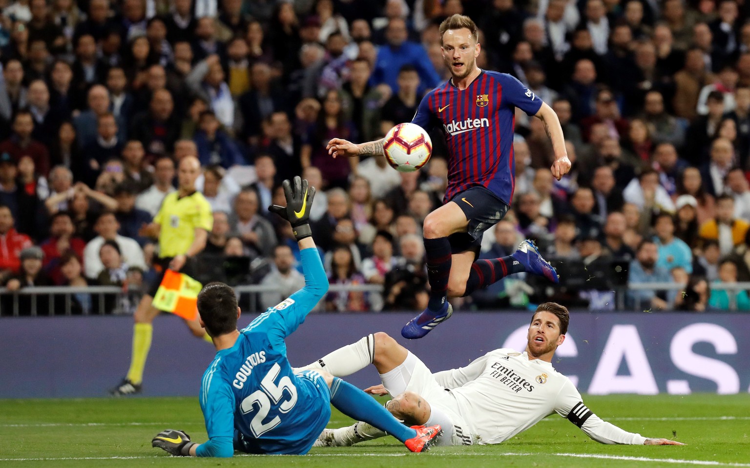 epa07409553 FC Barcelona&#039;s Ivan Rakitic (top) beats Real Madrid&#039;s goalkeeper Thibaut Courtois (bottom) and Sergio Ramos (R) to score the 0-1 lead during a Spanish LaLiga soccer match between ...