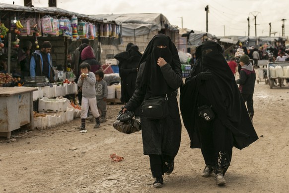 FILE - In this March 31, 2019, file, photo, women shop in the marketplace at al-Hol camp, home to families of Islamic State fighters, in Hasakeh province, Syria. As Turkish troops invade northern Syri ...