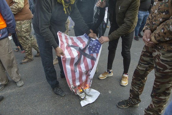 Mourners burn a U.S. flag during the funeral of Iran&#039;s top general Qassem Soleimani and Abu Mahdi al-Muhandis, deputy commander of Iran-backed militias in Iraq known as the Popular Mobilization F ...