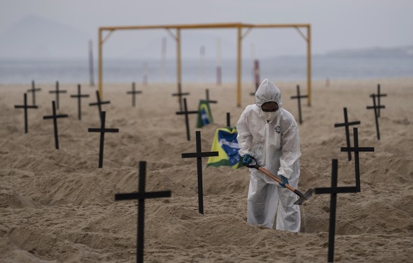 An activist digs symbolic graves on Copacabana beach, in front of a soccer goalpost, during a protest organized by the NGO Rio de Paz against the government&#039;s handling of the COVID-19 pandemic in ...