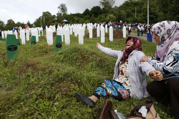 Bosnian Muslim woman Senija Rizvanovic, left, cries near the graves of her two sons in Srebrenica, Bosnia, Friday, July 11, 2014. Thousands of people gathered at the Potocari Memorial Center for a mem ...