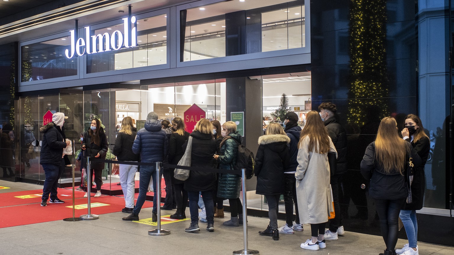 Menschen mit Atemschutzmasken stehen vor dem Warenhaus Jelmoli Schlange um einkaufen zu duerfen, aufgenommen am Samstag, 19. Dezember 2020 in Zuerich. (KEYSTONE/Ennio Leanza)