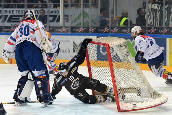 Zurich&#039;s goalkeeper Lukas Flueeler, left, fights for the puck with Lugano’s player Alessio Bertaggia, right, during the fifth match of the playoff final of the National League of the ice hockey S ...