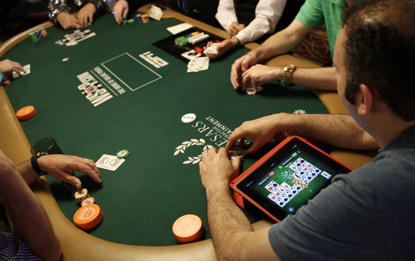 Abe Mosseri plays a game on his iPad while also playing on the first day of the World Series of Poker main event Saturday, July 5, 2014, in Las Vegas. Players are vying for the $10 million first-place ...